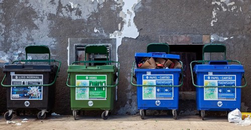 Dustbin in front of an old house wall