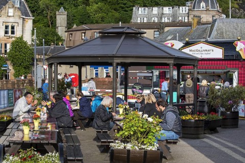 Tourists eating seafood at fish and chips stand in the city Oban