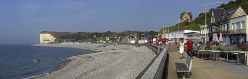 Pebble beach and tourists at pavement cafe on promenade at Veulettes-sur-Mer