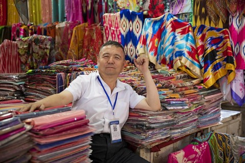 Uyghur vendor selling colourful cloth in fabric store