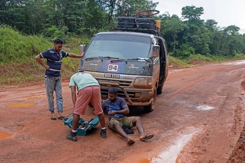 Driver repairing broken down minibus in the rain forest along the Linden-Lethem dirt road linking Lethem and Georgetown