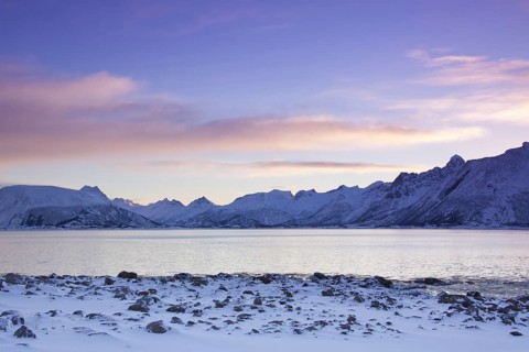 View over the Gimsoystraumen fjord and mountains in the snow in winter at sunrise
