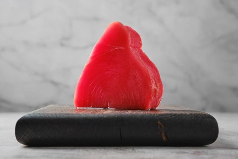 One piece of ahi tuna steak on wooden cutting board