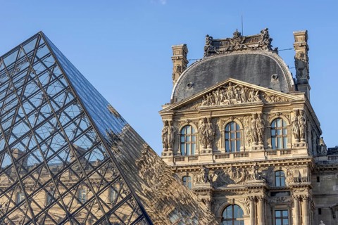 Detail of the Louvre Museum building with reflection on the glass pyramid