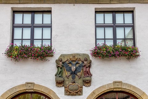 Detail of a building with two windows and coat of arms in the centre
