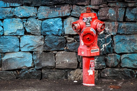 Red fire hydrant in front of a stone wall