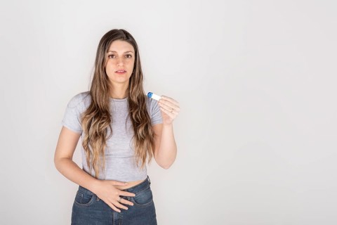 Portrait of a young blond woman holding pregnancy test feeling shocked
