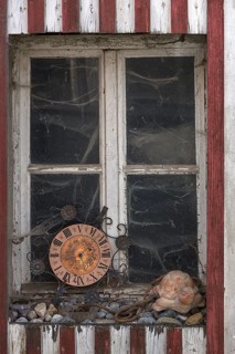 Window of an old farmhouse with cobwebs and old kitchen clock