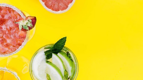 Glasses with strawberry lime cocktails yellow background