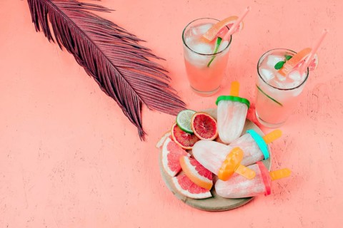 Grapefruits slices juice popsicles with leaf coral textured background