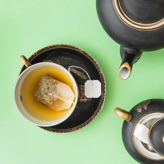 Herbal tea bag cup with teapot sugar cubes green background