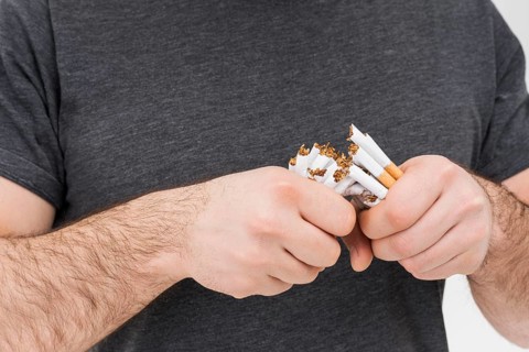 Mid section man breaking cigarettes with hands
