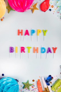 Overhead view colorful happy birthday candles with party items white backdrop