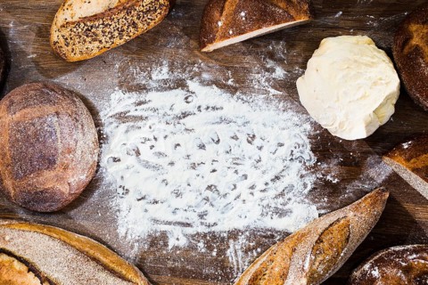 Overhead view loaf bread baguette kneaded dough with flour wooden desk