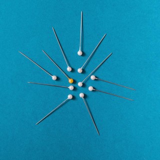 Overhead view yellow push pins with white pins blue background