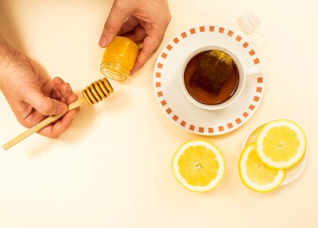 Person s hand peaking honey from jar healthy tea