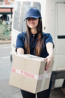 Portrait smiling female courier with cardboard box