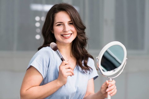 Portrait young brunette with makeup brush mirror