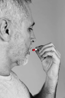 Senior man taking red white capsule