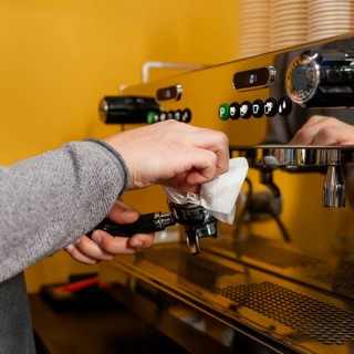 Side view male barista cleaning professional coffee machine