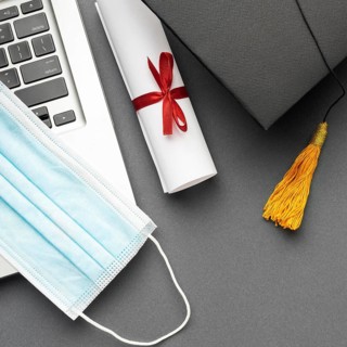 Top view laptop with medical mask academic cap