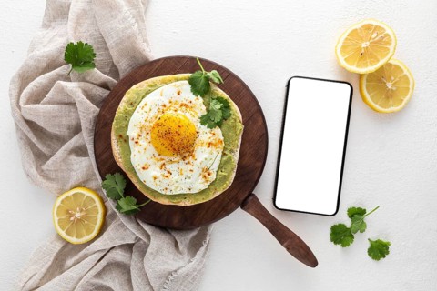 Top view pita with avocado spread fried egg with blank phone