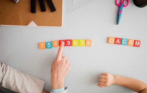 Top view tutor teaching child desk about numbers letters