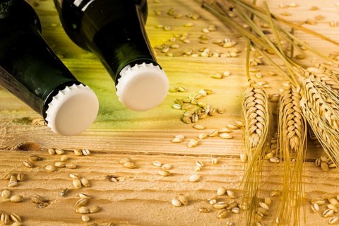 Two beer bottles ears wheat wooden backdrop