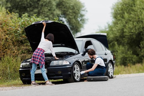 Woman checking engine man swapping tire
