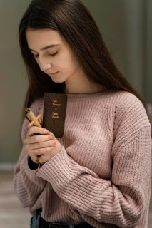 Woman praying with wooden cross bible