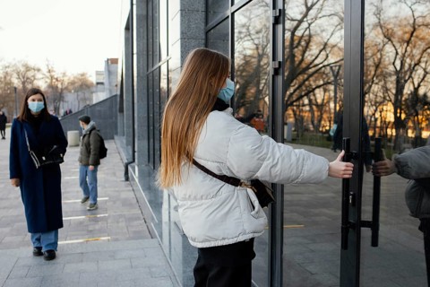 Woman with mask opening door