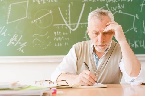 Aged tired teacher writing notebook classroom
