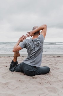 Back view man beach exercising yoga