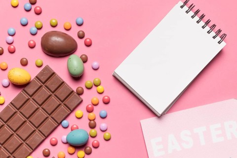Blank spiral notepad easter word easter eggs multicolored gem candies pink backdrop