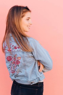 Blonde smiling young woman with her arms crossed against pink background