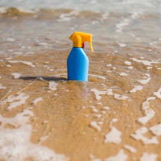 Blue sunscreen plastic bottle shallow sea water beach