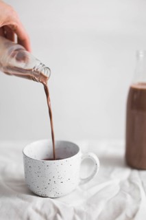 Close up person pouring chocolate milkshake white cup