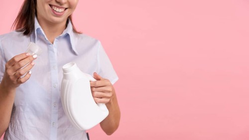 Close up woman holding detergent laundry bottle