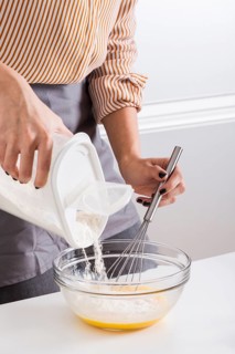 Close up woman s hand adding flour bowl