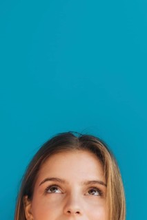 Close up young woman s face looking up against blue backdrop