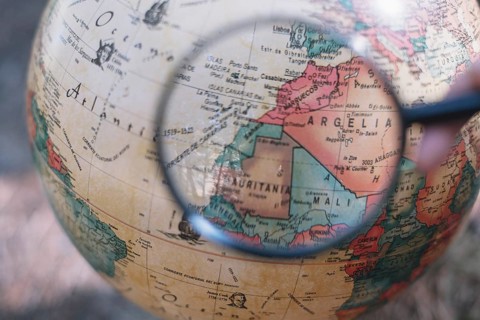 Crop hand with magnifying glass globe