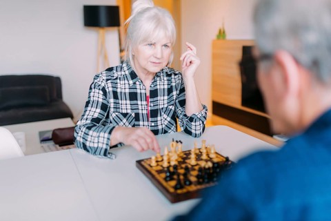 Elderly couple playing chess retirement home