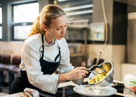Female chef pouring food plate