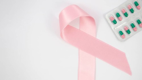 Flat lay pink ribbon pills arrangement