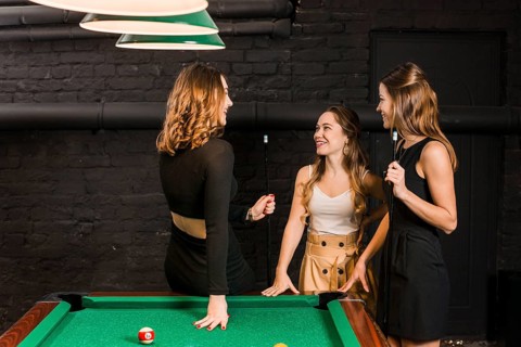 Group happy female friends standing near snooker table