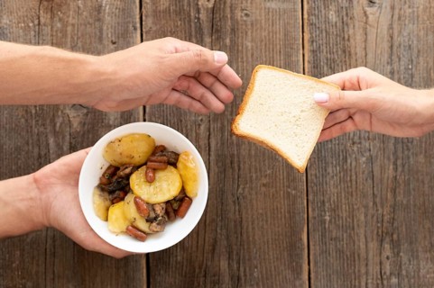 Hand giving bowl food bread needy person