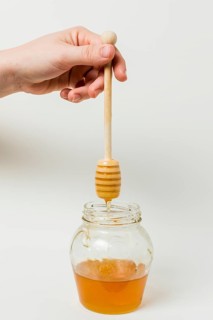 Hand holding honey spoon