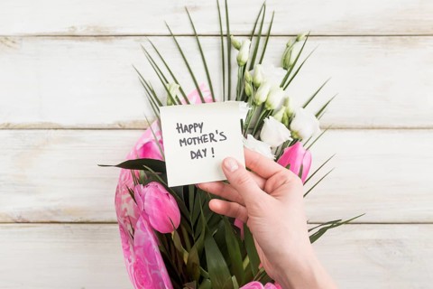 Hand with happy mothers day sticker bouquet