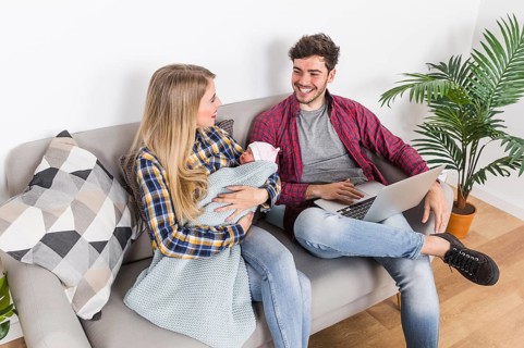 Happy parents with sleeping baby using laptop