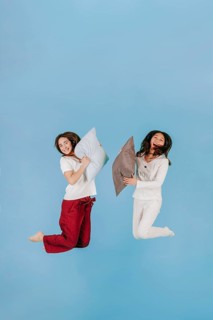 Laughing women jumping with pillows